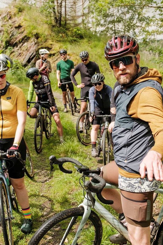 Eine Gruppe von Radfahrerenden macht Halt auf einem Waldweg und schaut nach dem richtigen Weg.