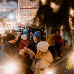 Eine Personengruppe steht zum Weihnachtsmarkt auf dem Marktplatz in Wernigerode unter dem Weihnachtsbaum und trinkt Glühwein.