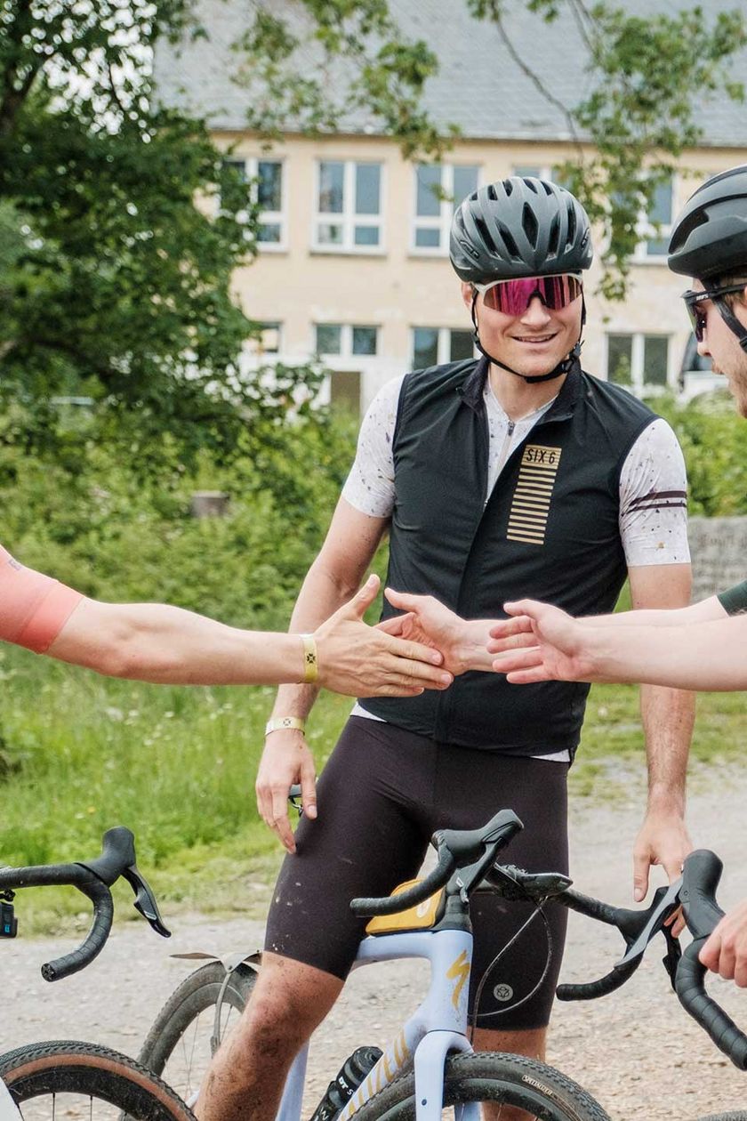 Eine Gruppe von Fahradfahrenden reicht sich in der Mitte die Hände.