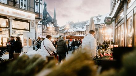 Besucher des Weihnachtsmarktes in Wernigerode gehen an Hütten vorbei auf den Marktplatz