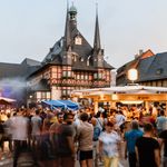 Vor dem Rathaus auf dem Marktplatz in Wernigerode stehen viele Menschen an Gastronomieständen zum Rathausfest in Wernigerode.