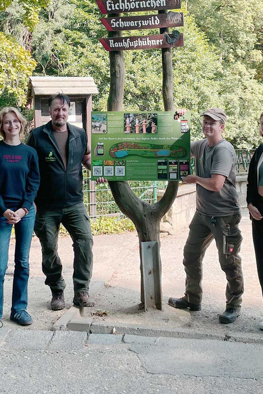 Zur Eröffnung der Rallye durch den Wildpark Christianental steht eine Gruppe von Personen und hält ein Schild in der Mitte.