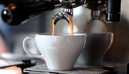 Eine Kaffeetasse wird von einer Kaffeemaschine gefüllt.