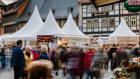 Auf dem Marktplatz von Wernigerode stehen Stände zum Schokoladenfestival chocolART. Menschen laufen entlang der Verkausstände.