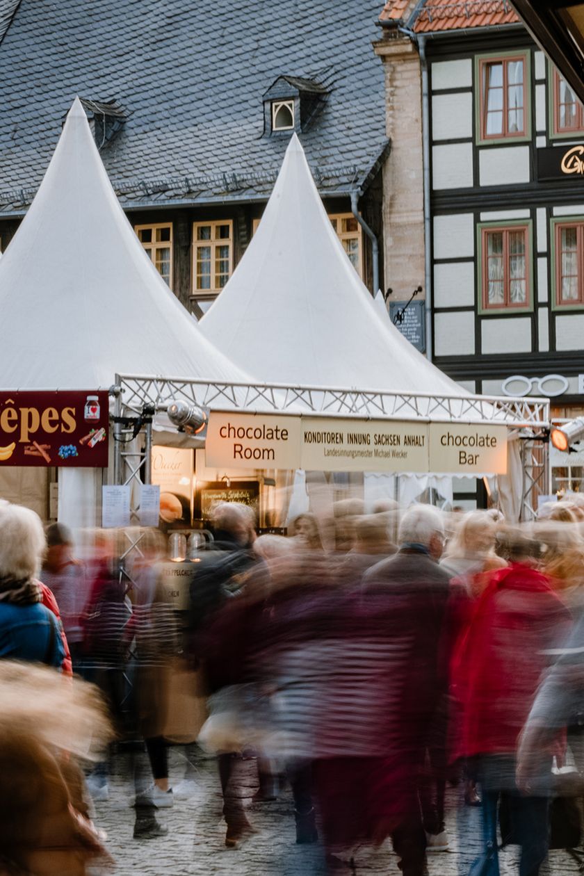 Auf dem Marktplatz von Wernigerode stehen Stände zum Schokoladenfestival chocolART. Menschen laufen entlang der Verkausstände.