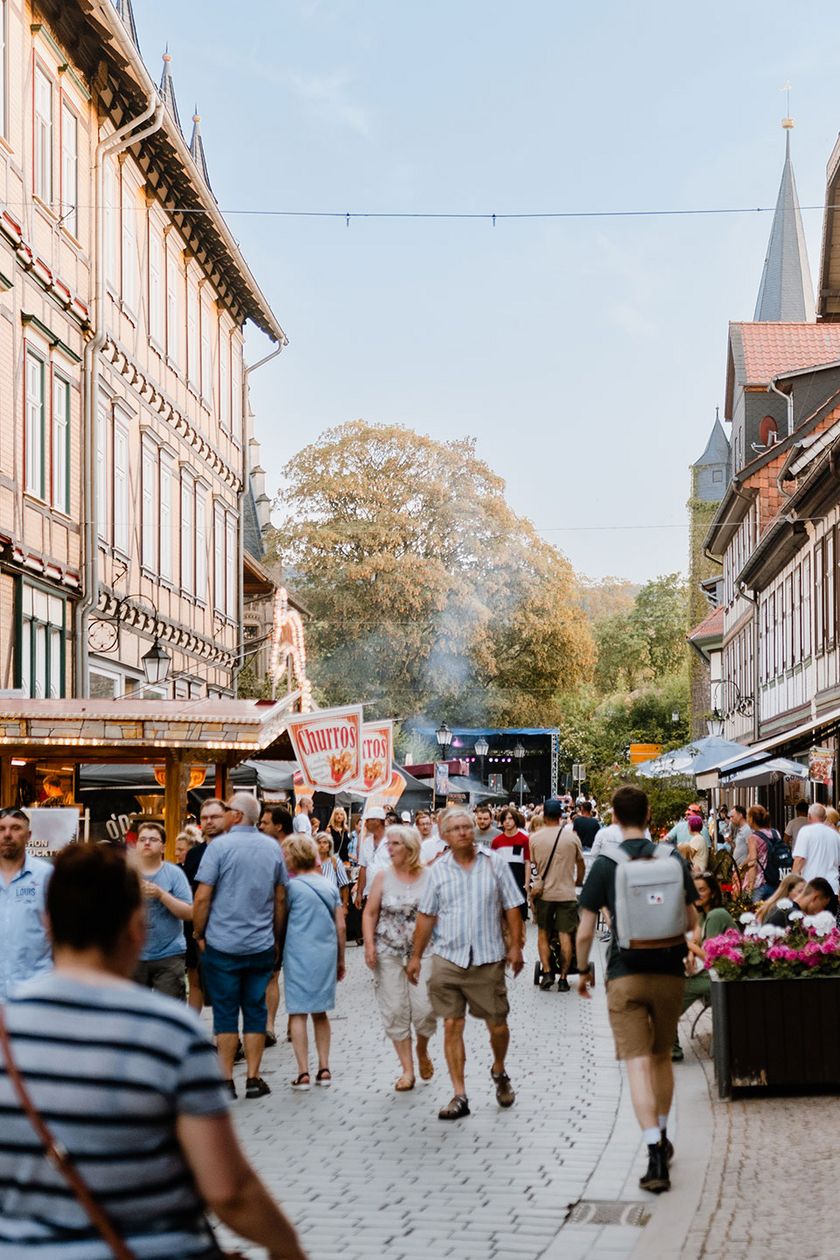 Gäste des Rathausfest in Wernigerode laufen durch die Westernstraße zu einer Bühne im hinteren Bereich.