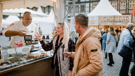 Ein Paar steht vor einem Verkaufsstand zum Schokoladenfestival chocolART in Wernigerode auf dem Marktplatz.