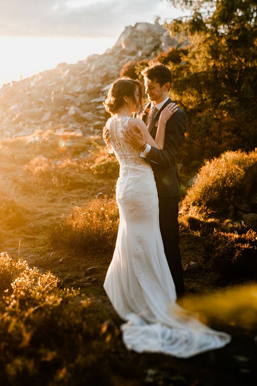 Ein Hochzeitspaar steht an der Wolfswarte im Gegenlicht und schaut sich an.