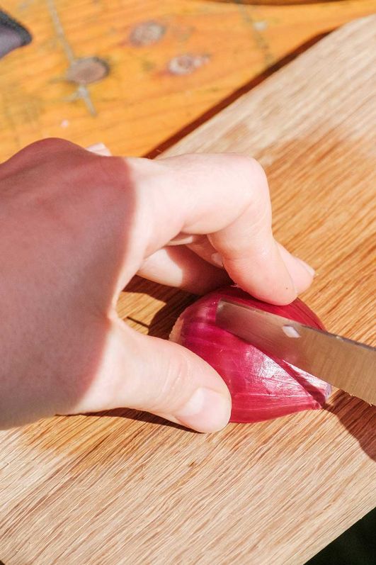 Teilnehmer des Gravel Bike Festes schneidet eine Zwiebel während eines Kochkurses