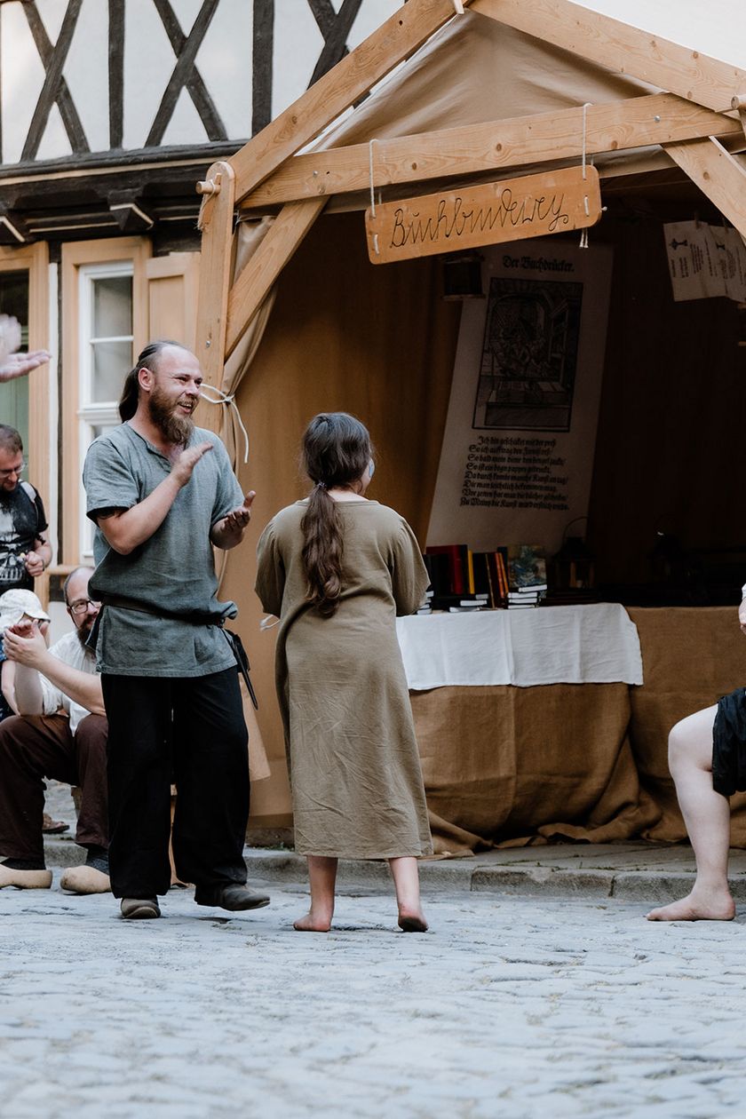 Personen stehen vor einem Stand auf dem Mittelaltermarkt zum Rathausfest in Wernigerode.