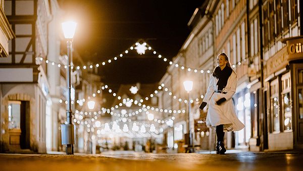 Frau läuft die beleuchtete Breite Straße in Wernigerode entlang