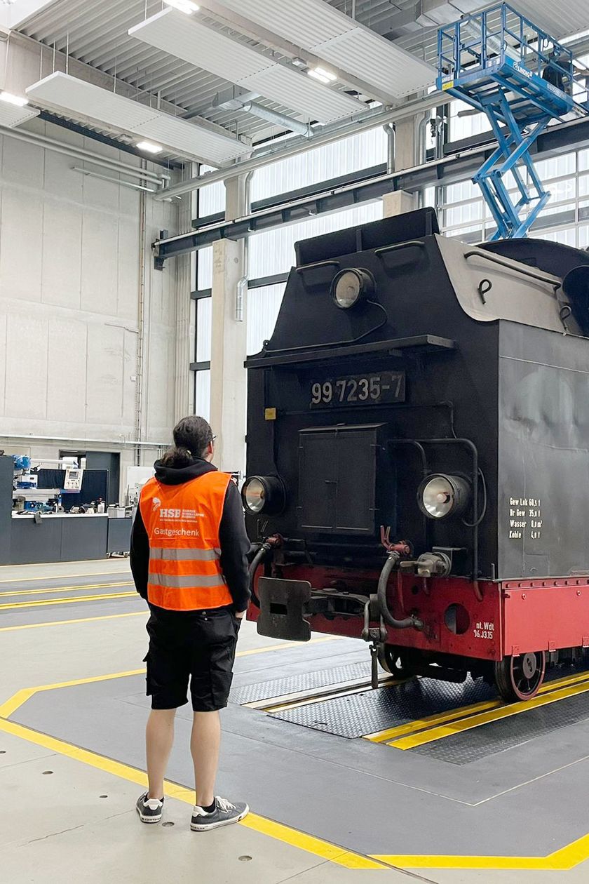 Personen stehen während einer Filmproduktion in der Dampflokwerkstatt der Harzer Schmalspurbahnen in Wernigerode