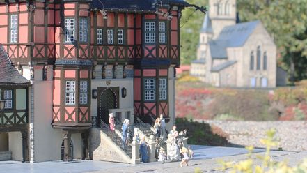 Im Miniaturenpark Kleiner Harz steht eine Gruppe aus Miniaturen vor dem Rathaus in Wernigerode. Im Hintergrund ist eine KIrche zu sehen.