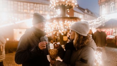 Ein Paar prostet sich mit Glühweinbechern auf dem Weihnachtsmarkt in Wernigerode zu.