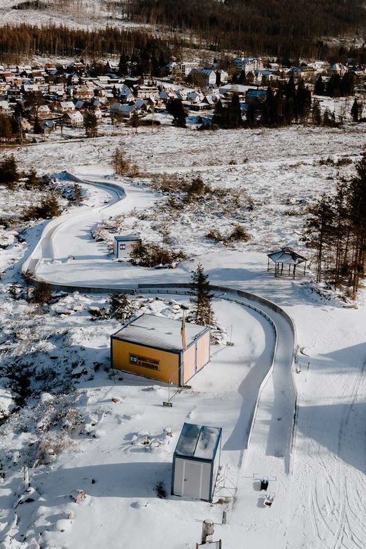 Luftaufnahme von der Rennrodelbahn in Schierke. Im Hintergrund ist der Ort zu erkennen.
