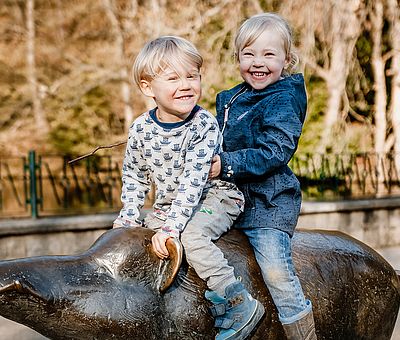 Kinder auf dem Bronzeschwein im Wildpark Christianental