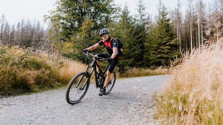 Ein Mountainbikefahrer fährt auf einer Schotterpist um eine Kurve